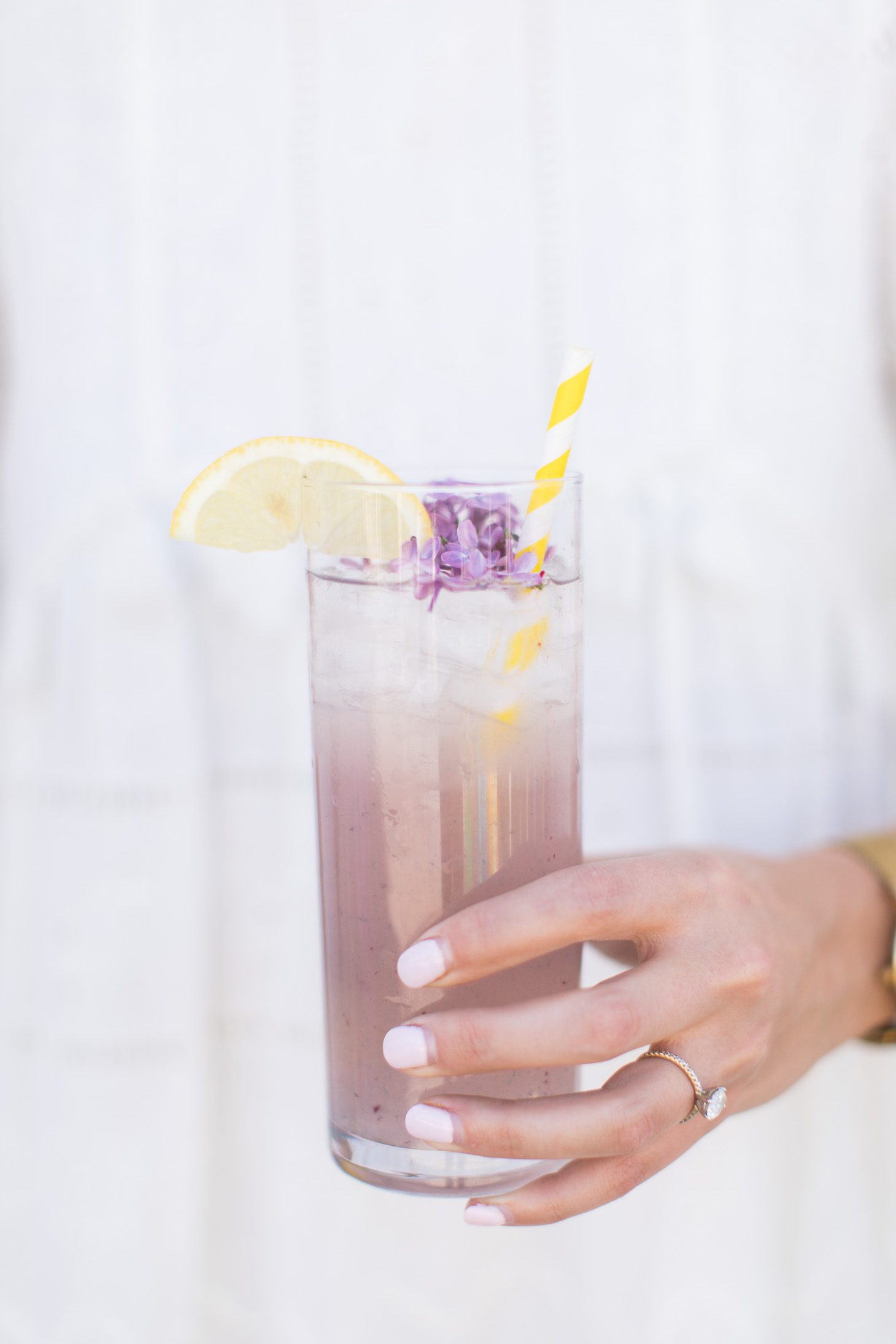 Jillian Harris' hand holding a glass of spiked blackberry lemonade.