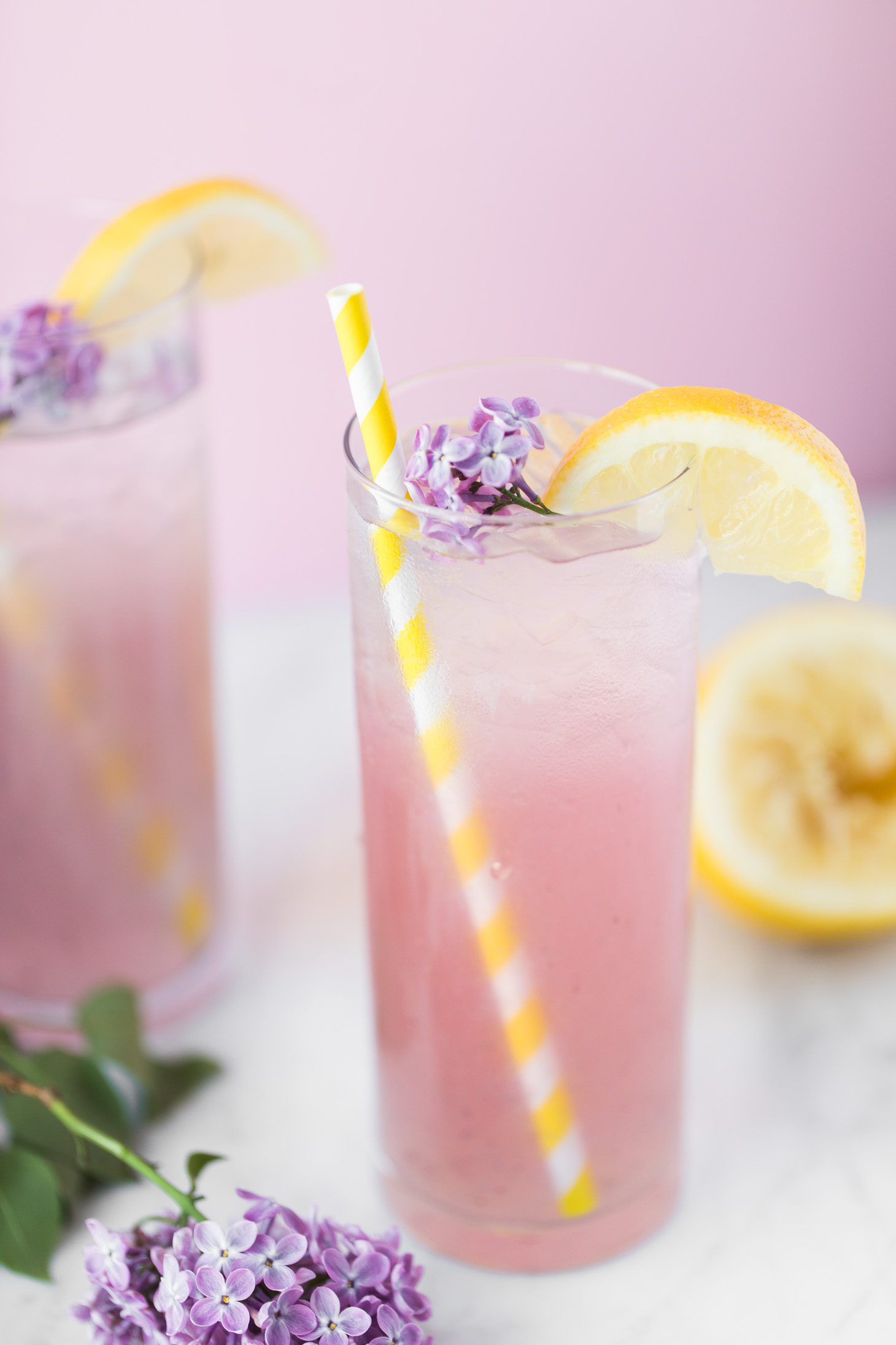 2 glasses of pink lemonade with yellow straws.