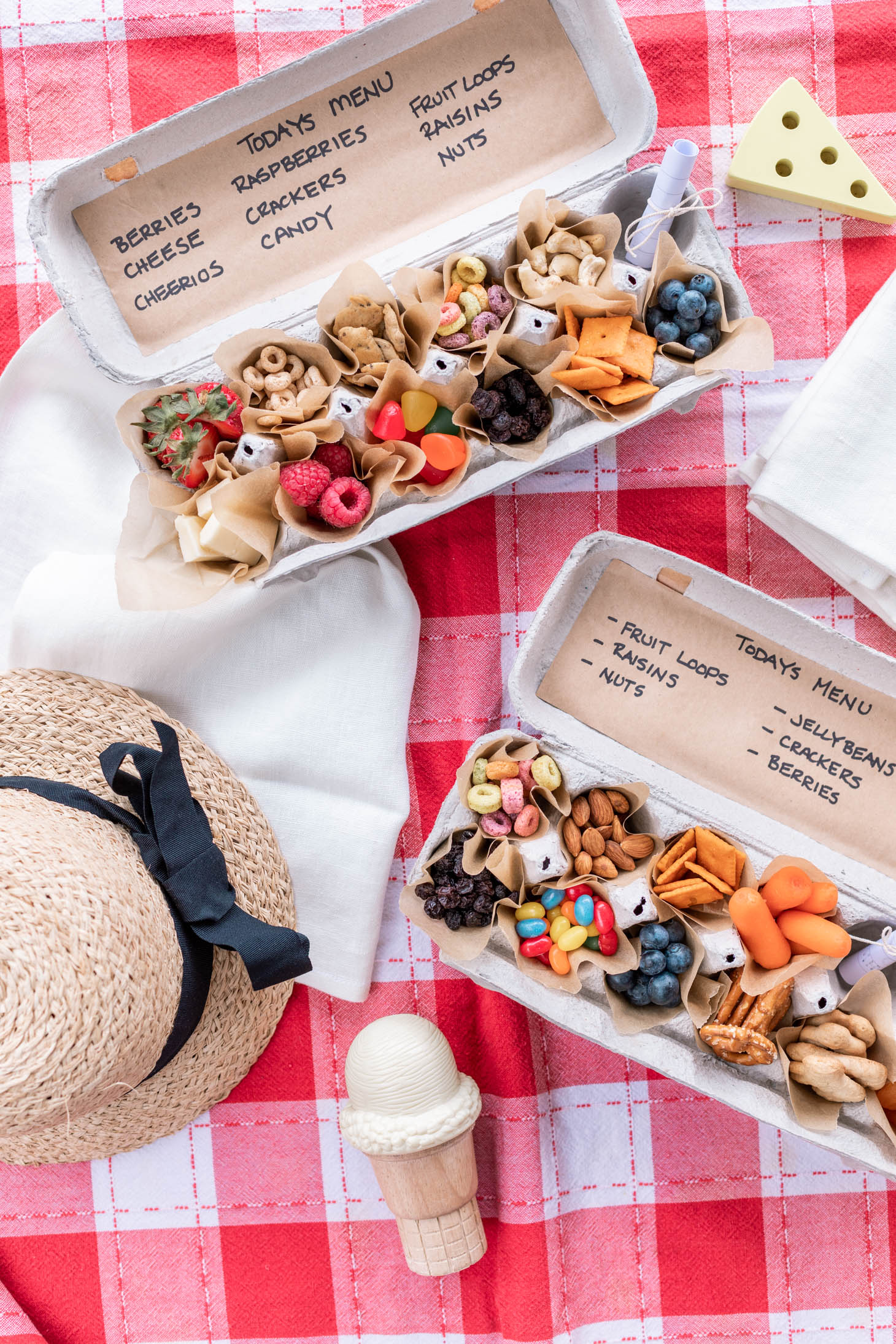 The inside of an Egg Carton that that is full of various small snacks of fruit, cereal, crackers, nuts, cheese and candy.