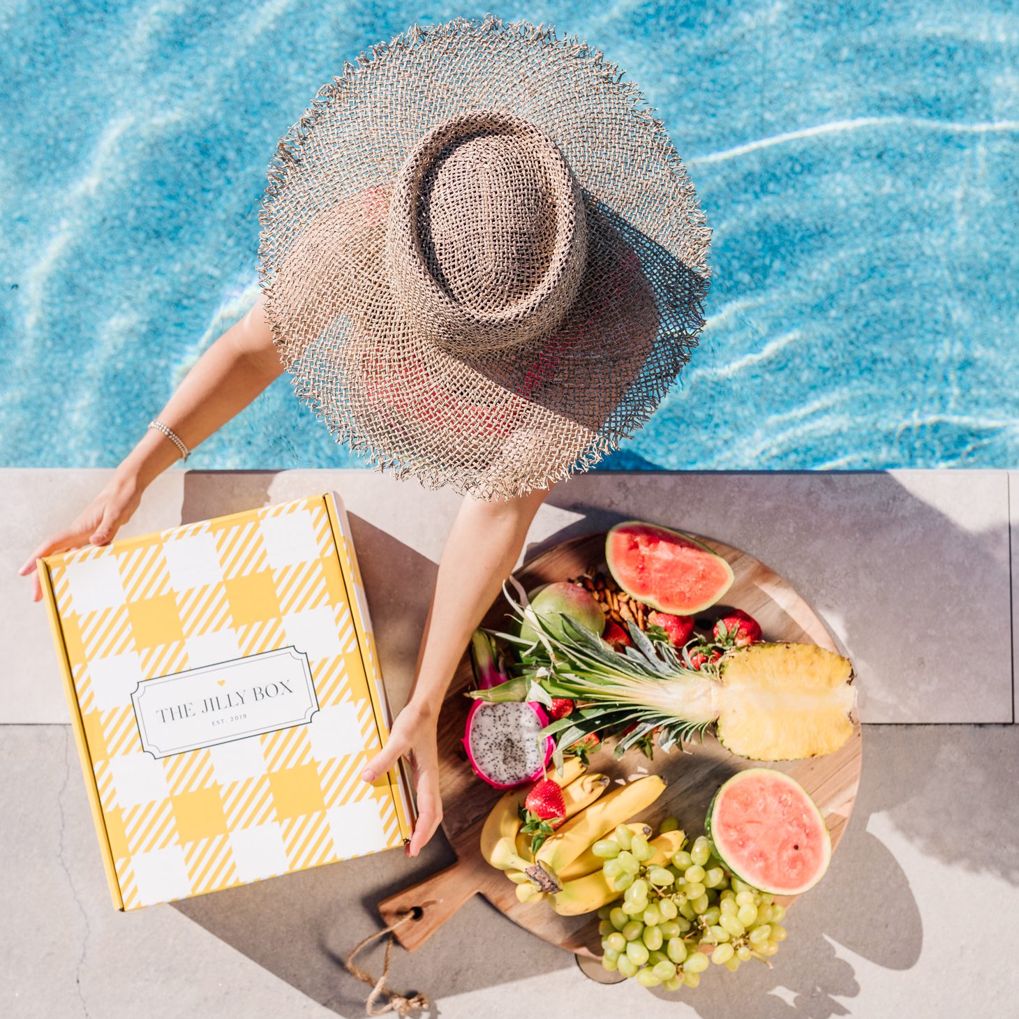 Jillian Harris in pool with fruit platter and the Summer 2020 Jilly Box