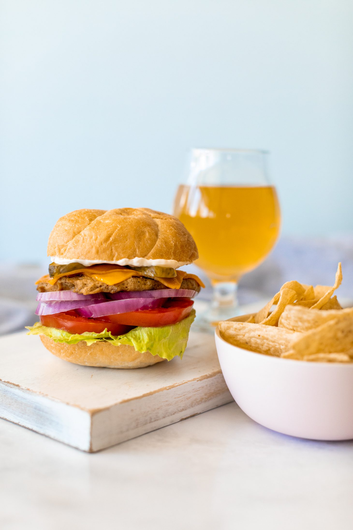 Vegetarian burger on a bun with lettuce, tomato, pickles, cheese, and red onion. 