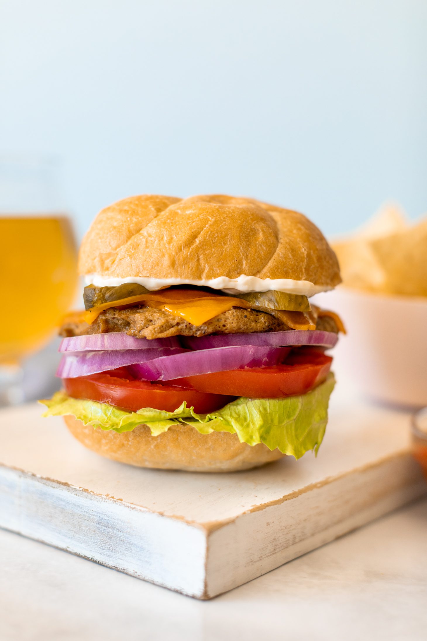 Plant-based burger with a bowl of tortilla chips and a pale ale beer.