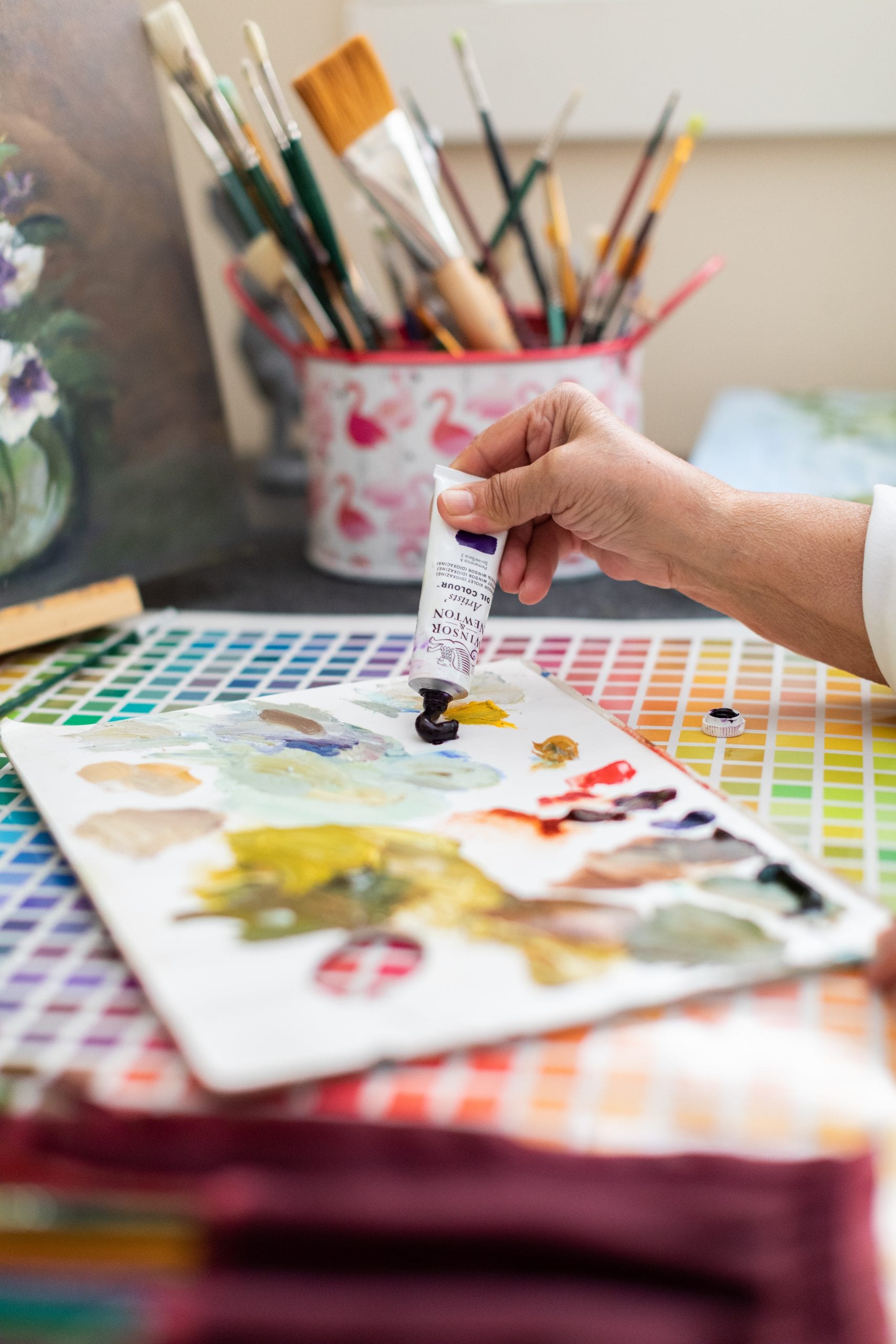 Peggy Harris applying dark purple oil paint to her painting palette. 