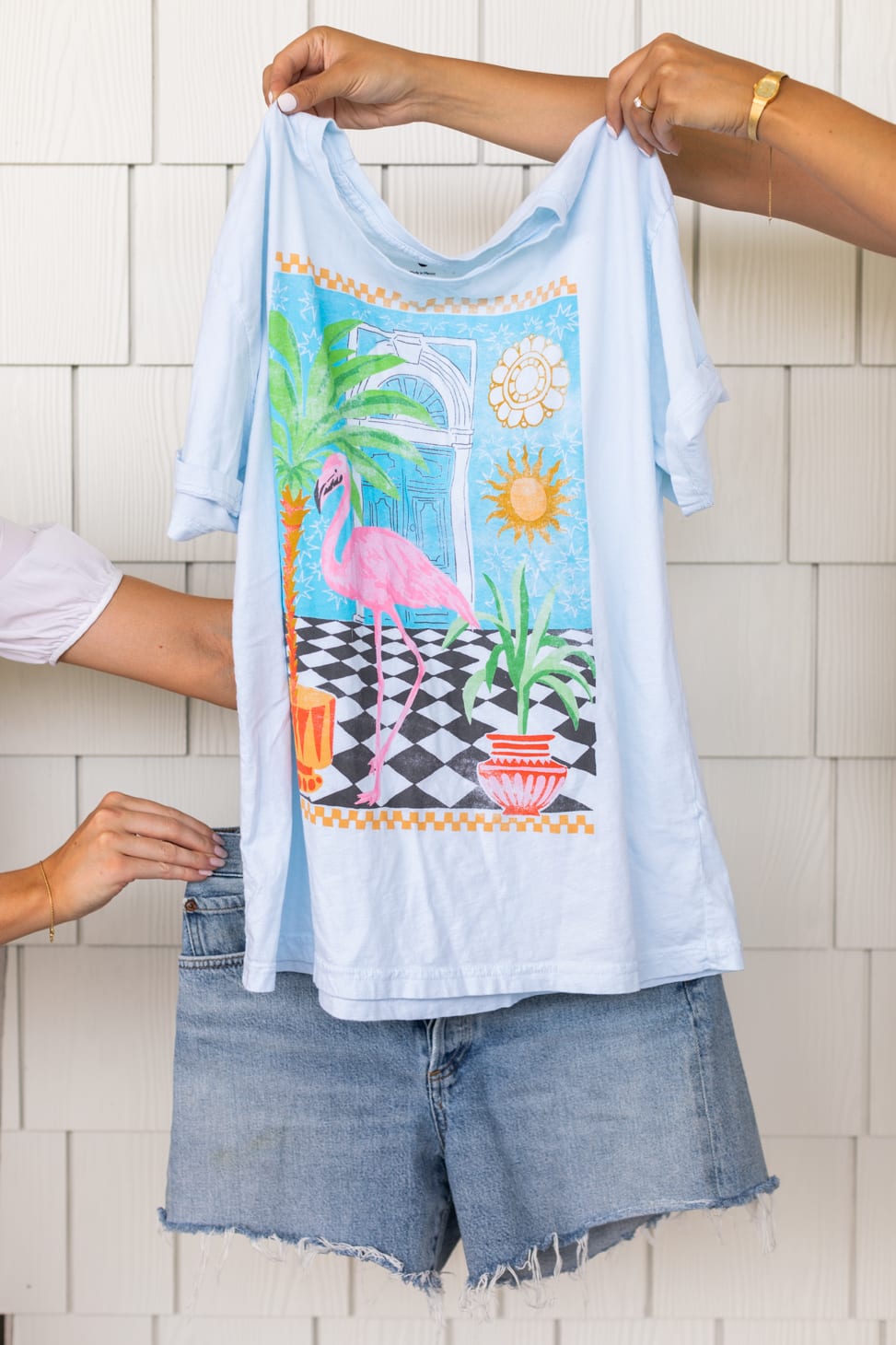 Jillian Harris' Farm-Inspired styled outfit showing a white t-shirt with a flamingo and tropical plants on it paired with distressed cut-off denim shorts.