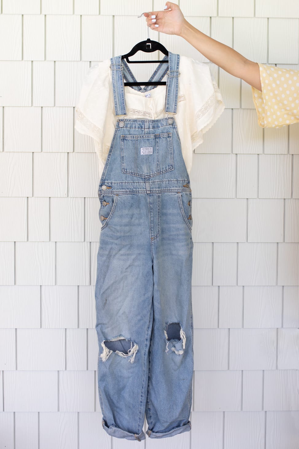 Light denim overalls with holes in knee area paired with a short sleeved white peasant shirt, an example of Jillian Harris' Favourite Farm-Inspired Looks.