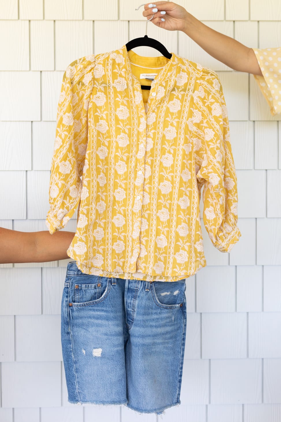 An outfit with yellow and white floral patterned button down shirt with Agolde mid-thigh cut-off denim shorts, one of her farm-inspired outfits.