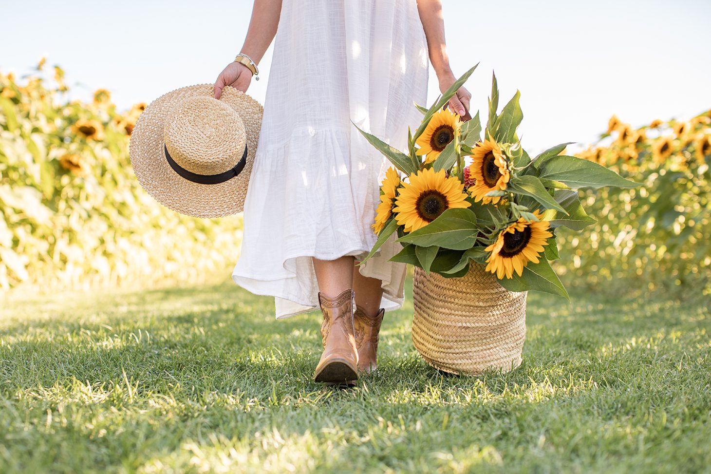 Jillian Harris with a basket of sunflowers and sunhat, a photo that is part of The Campus Store stock photo collections the Alumni love.