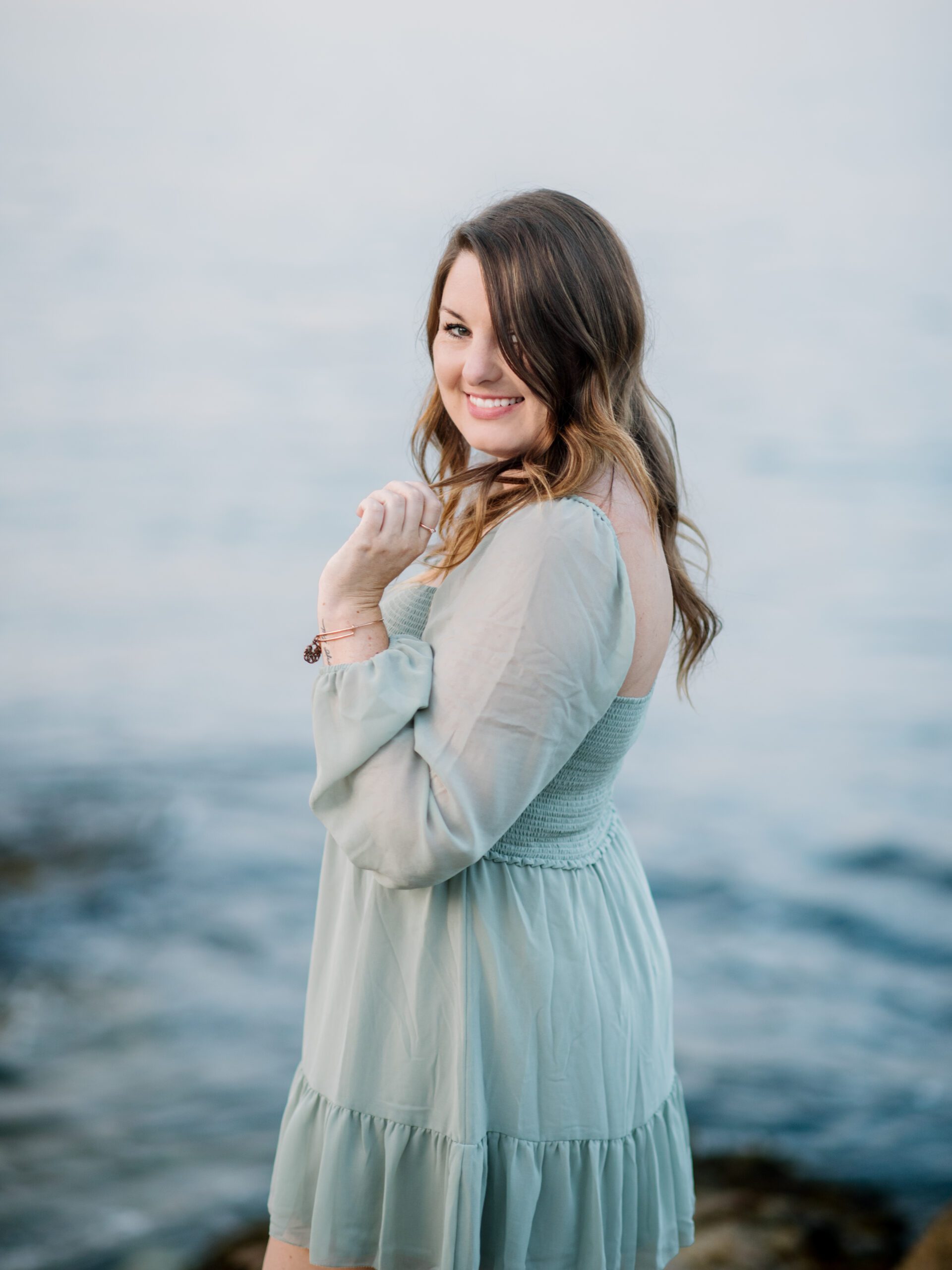 Jilly Academy Alumni member Katherine Jean posing near a lake wearing a blue dress expressing her creative side that lends to her self-care. 