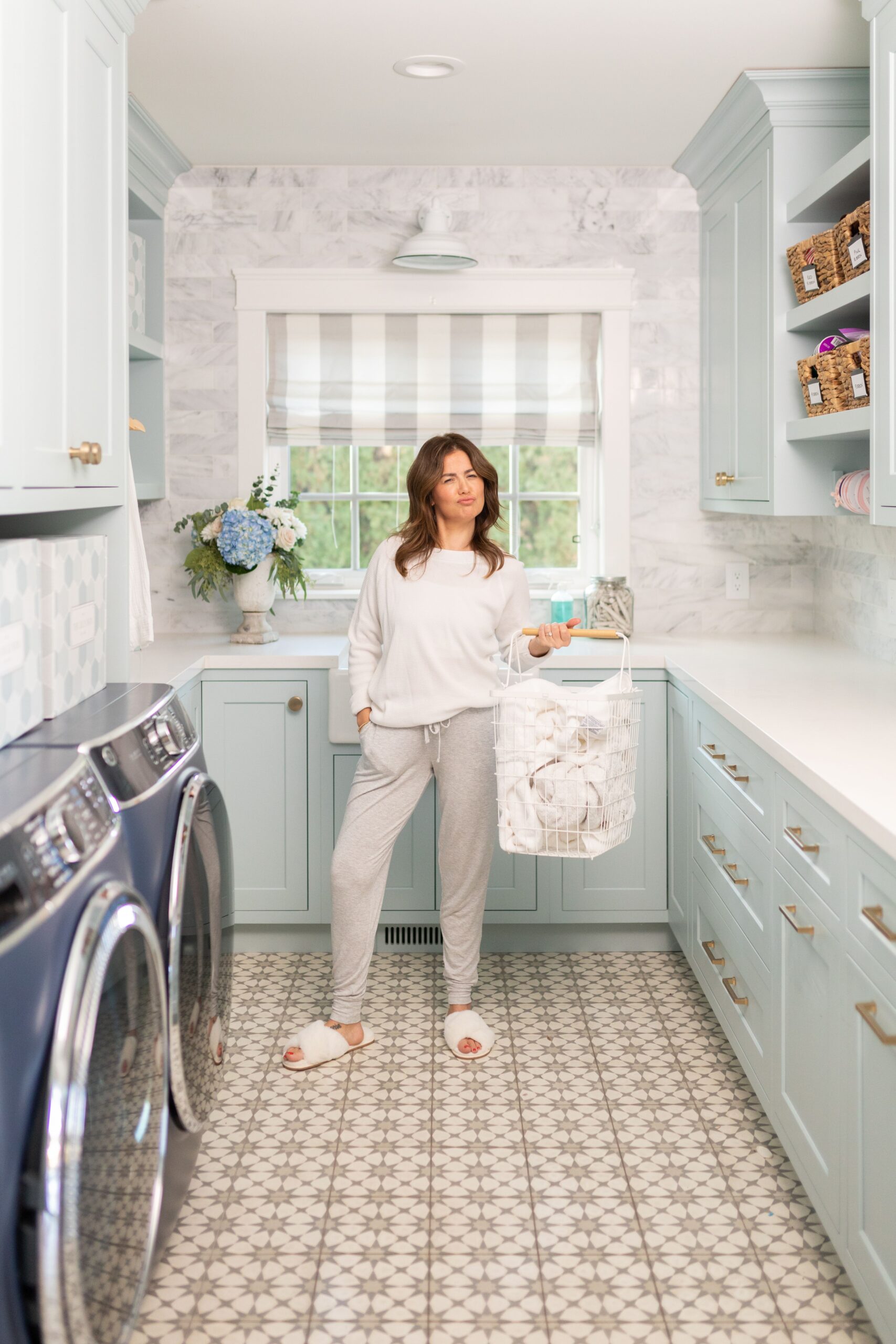 Jillian in her laundry room holding a laundry basket wearing the Knix Modal Lounge Pant