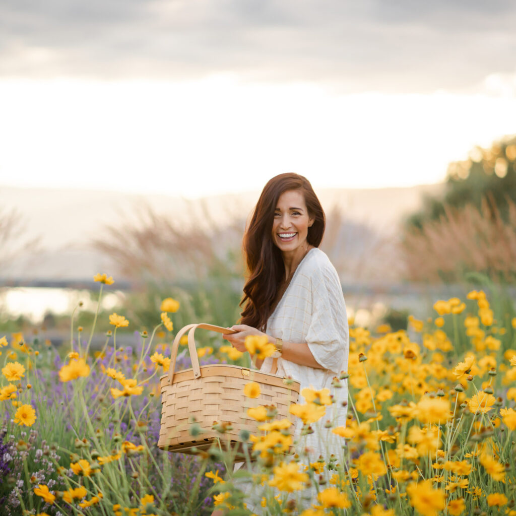 Tori Wesszer of Fraiche Table Meal in a field of yellow flowers holding a basket