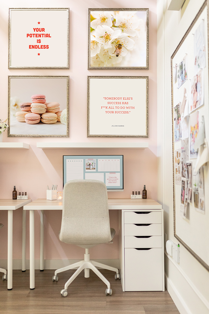 Jillian Harris' office showcasing the new digital prints and stock photos featured in our Campus Store on the wall. Top left is "your potential is endless", beside it is a bee on a cherry blossom photograph, below is a stack of pink macaroons, and next to it bottom right is "Somebody else's success has f*k all to do with your success." - Jillian Harris. Below the prints is a desk setup with the desktop organizer showing on screen.