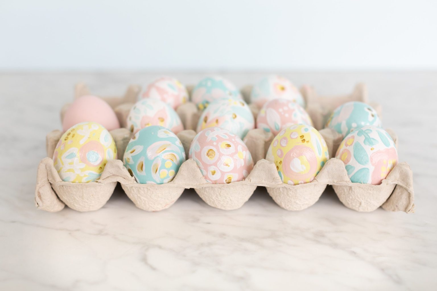 Pink, Yellow, and Blue painted Easter eggs in a carton