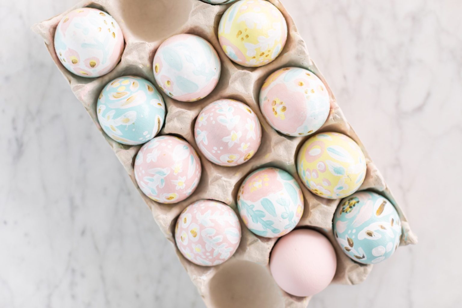 Overhead shot of pastel painted Easter eggs in a carton