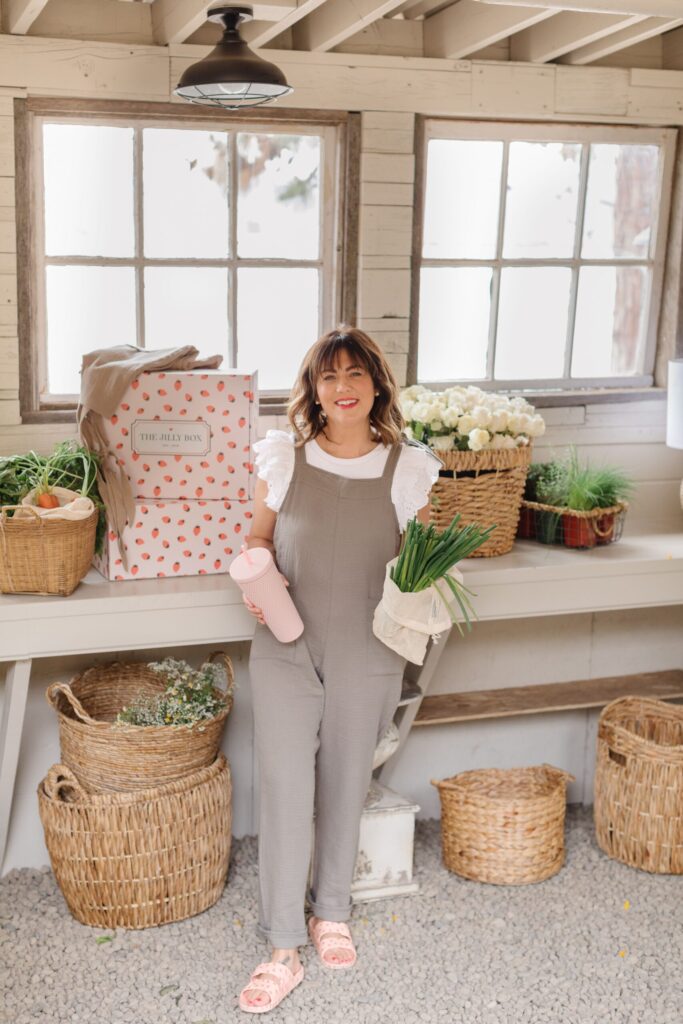 Jillian Harris holding the ASTOR Drinkware Custom Jilly Box Cup, the Better Farm Co Mesh Bags while wearing the Smash and Tess Jillyalls