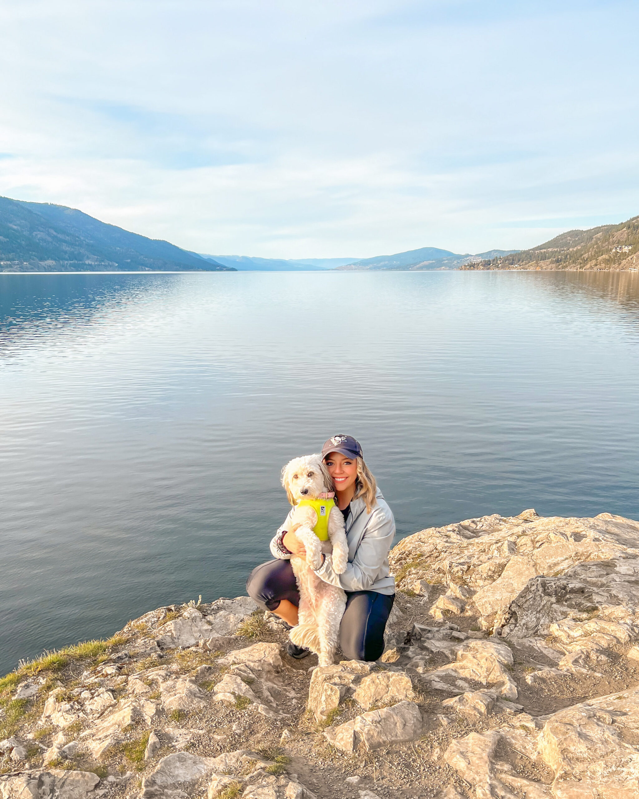 Alison of Team Jilly cuddling up to her dog on top of a mountain side overlooking the lake as part of her morning habits. 