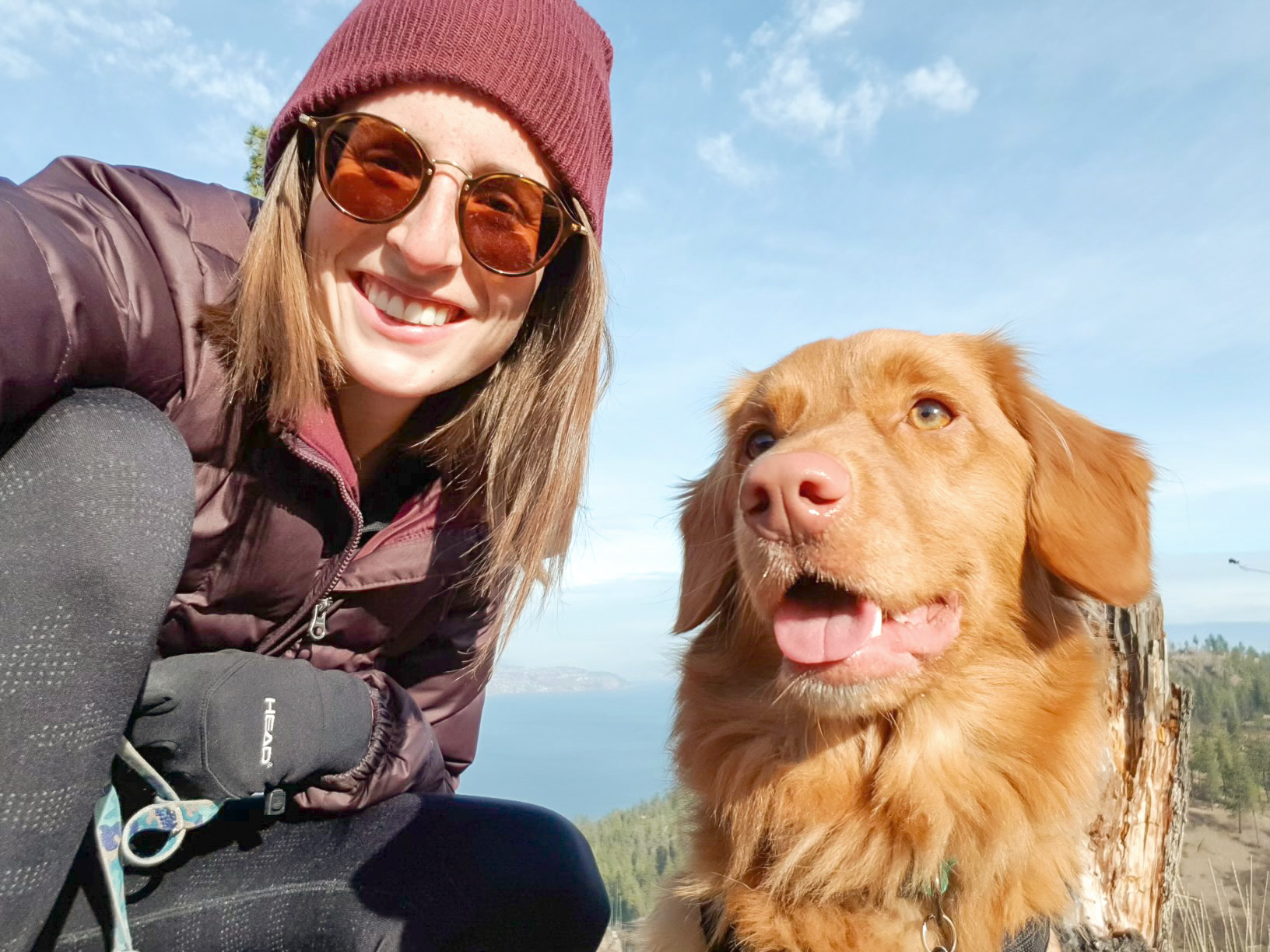 Jennifer of Team Jilly wearing hiking attire on top of a mountain kneeling down with her dog as she does her morning walk as part of her morning habits.