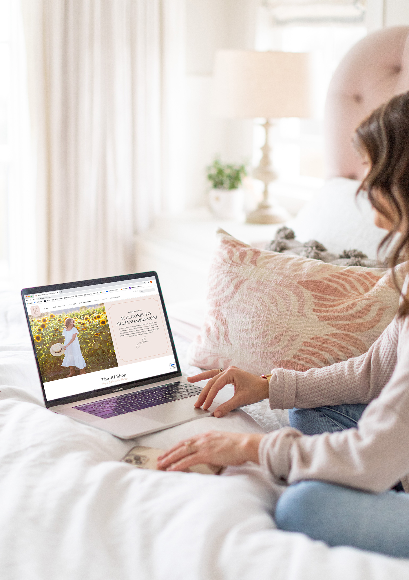 Jillian Harris sitting on her bed with her laptop showing her blog home page for owned platforms example. 