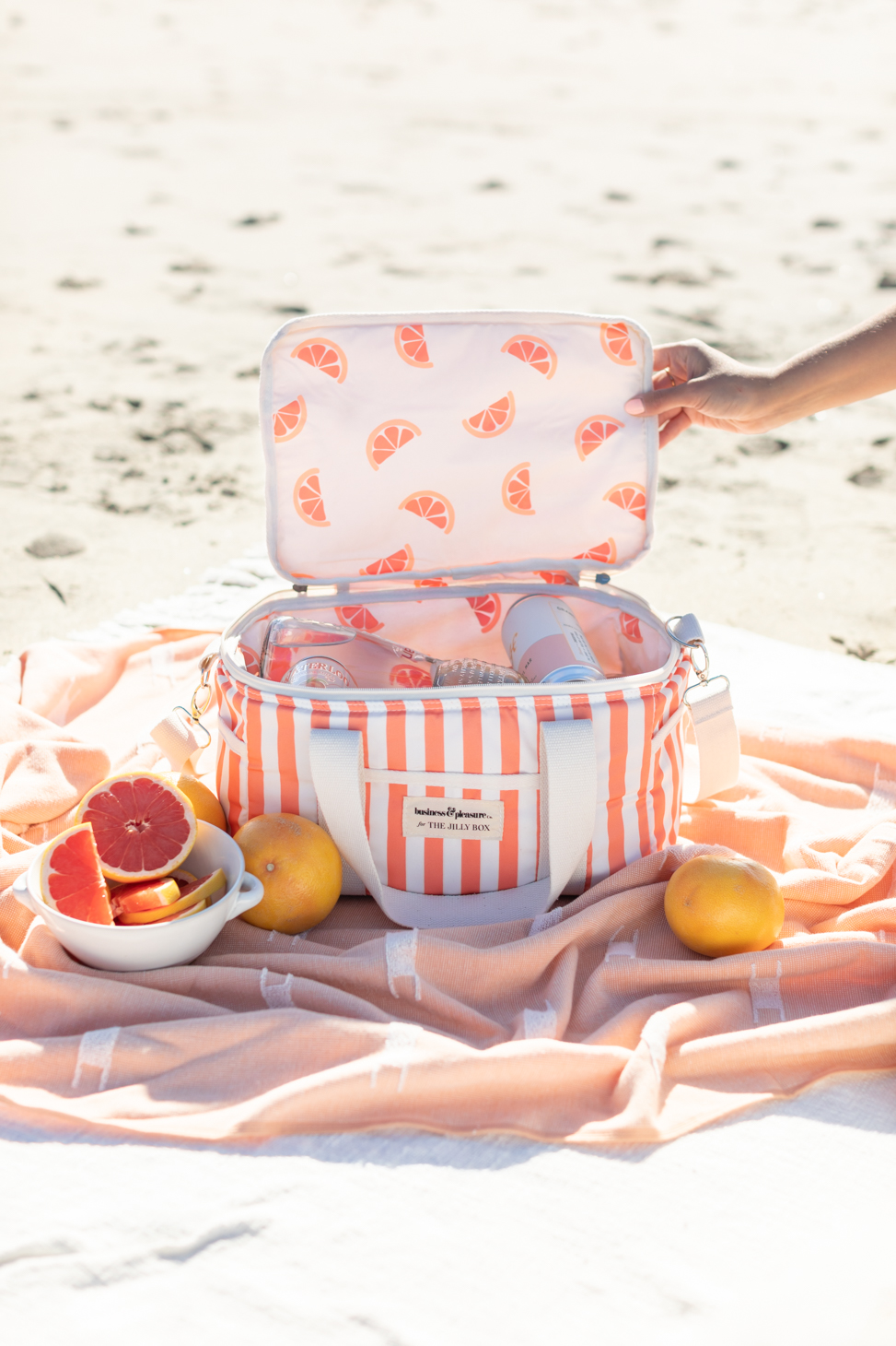 Cooler on beach towel with fruits and cans