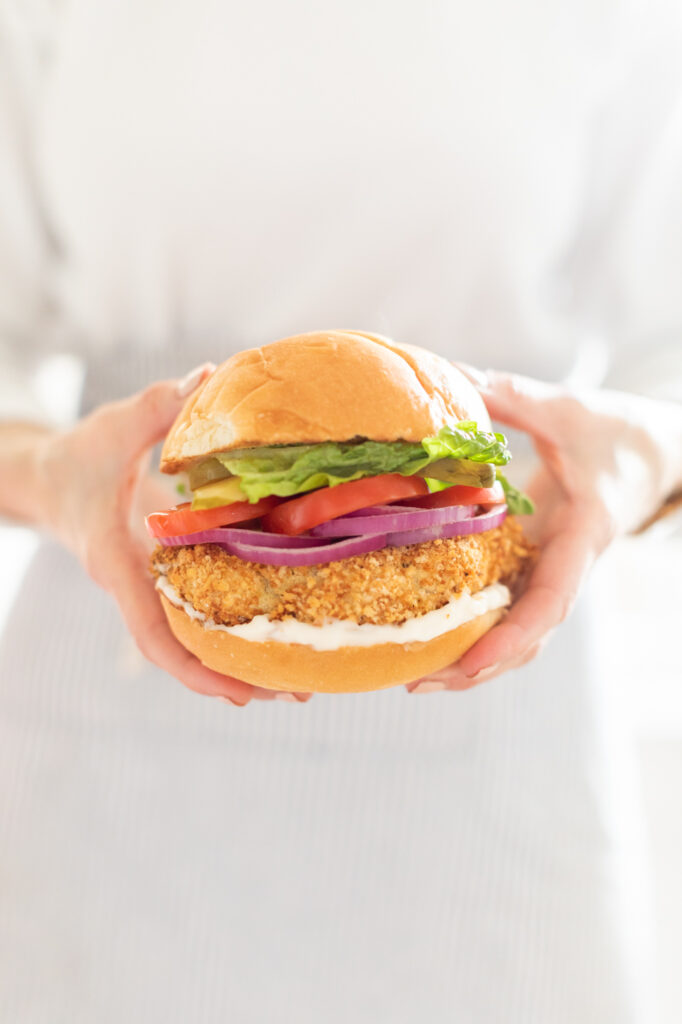 A breaded chicken sandwich with tomatoes, lettuce and onions, highlighting Fraiche Food, Fuller Hearts Mains