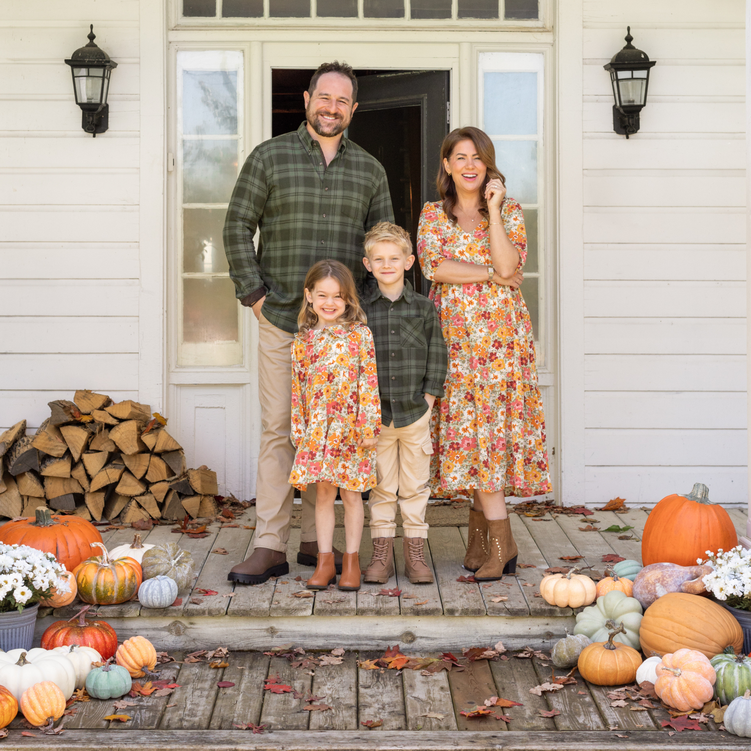 Jillian Harris and Justin Pasutto standing on the front porch with their children surrounded by fall pumpkins, wearing coordinated fall outfits.