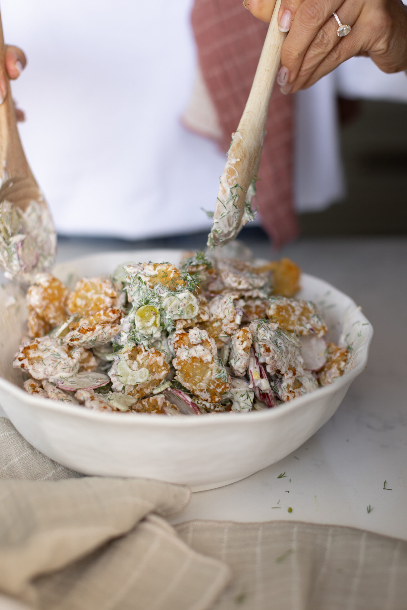 Adding the dressing and mixing the potato salad