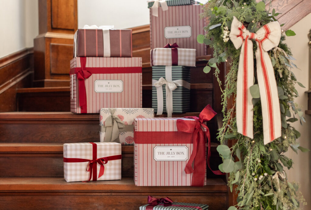 The Winter Jilly Boxes sitting on a staircase and decorated with red bows.