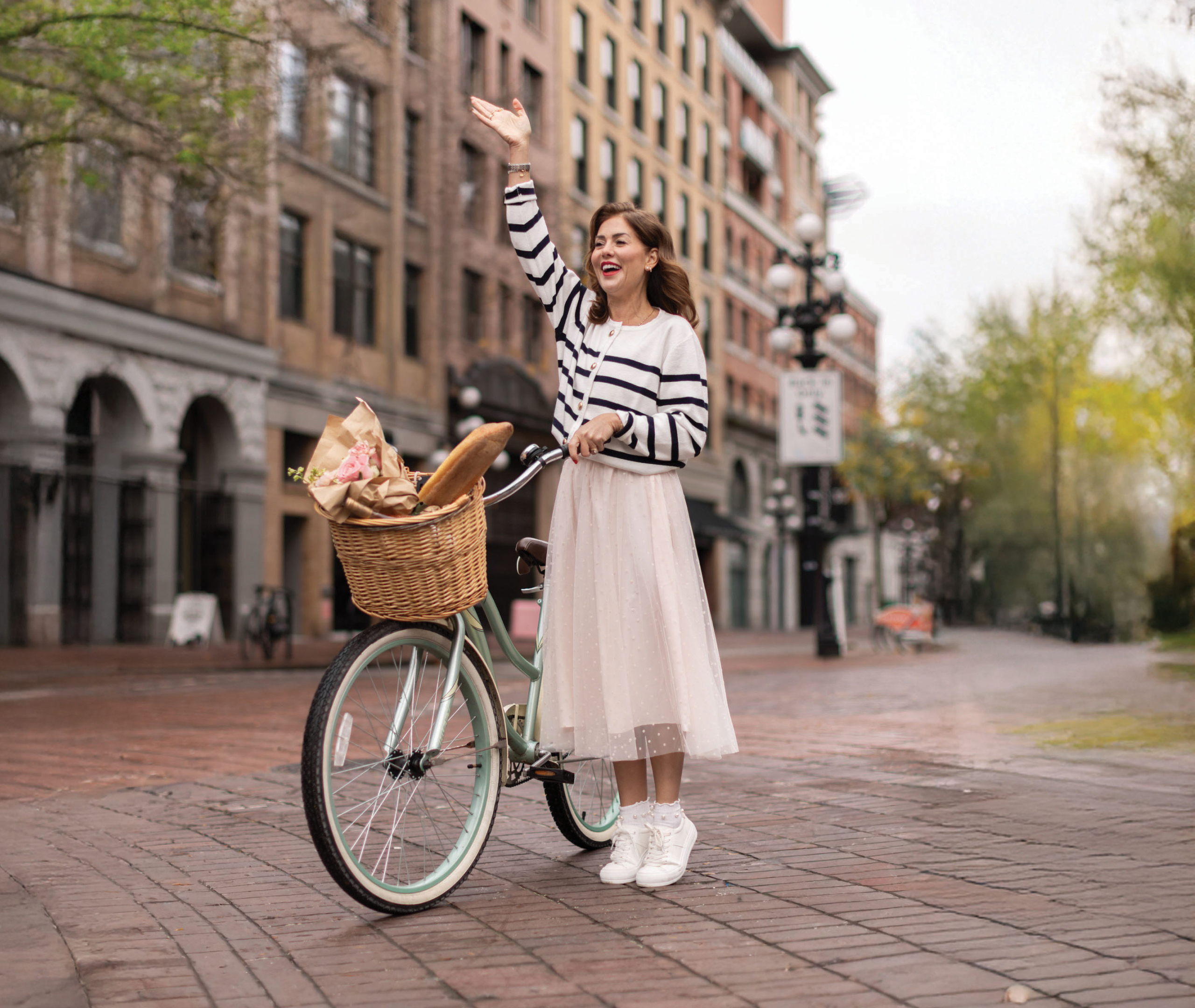 Jillian wearing the Rosalie Cardigan in Navy by a vintage bike on a historic street.