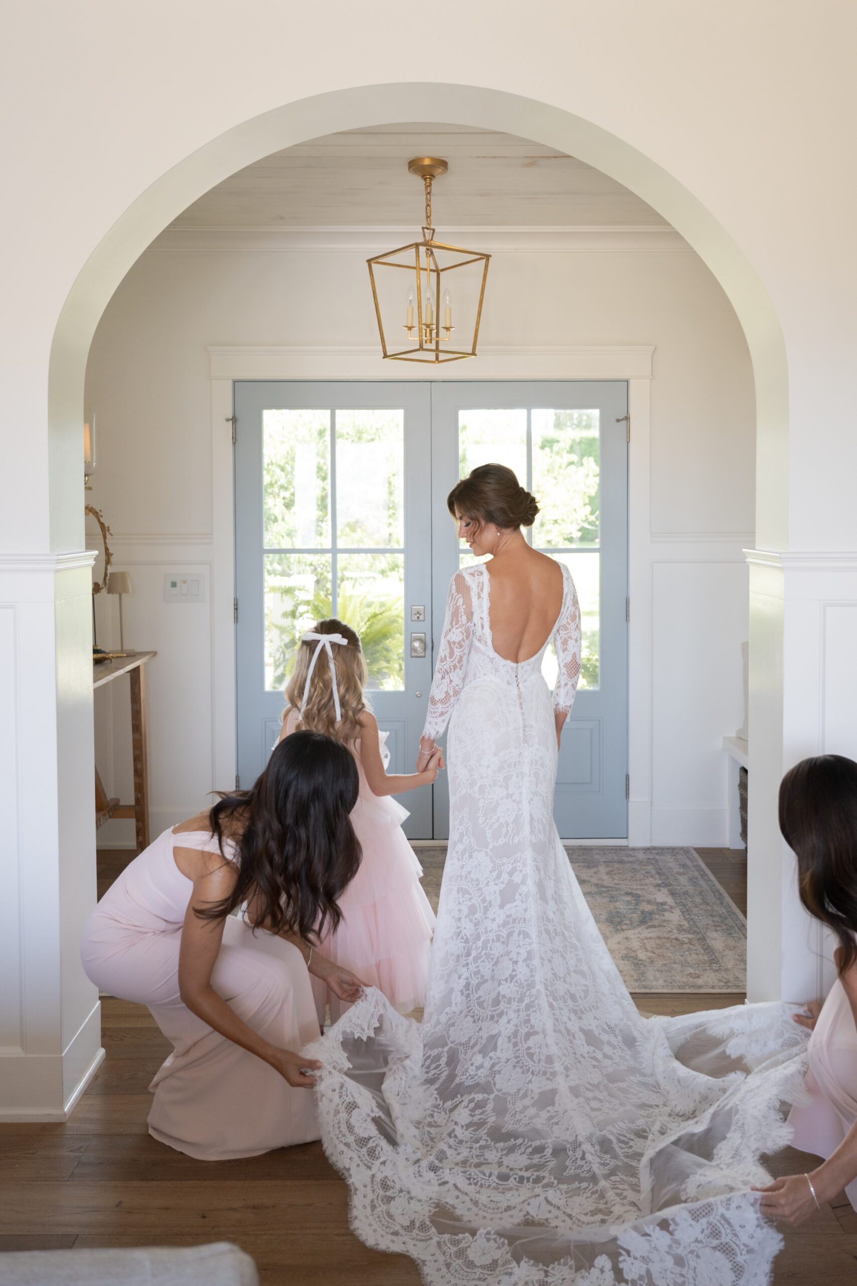 Sam adjusting the train on Jillian's long sleeve lace wedding dress