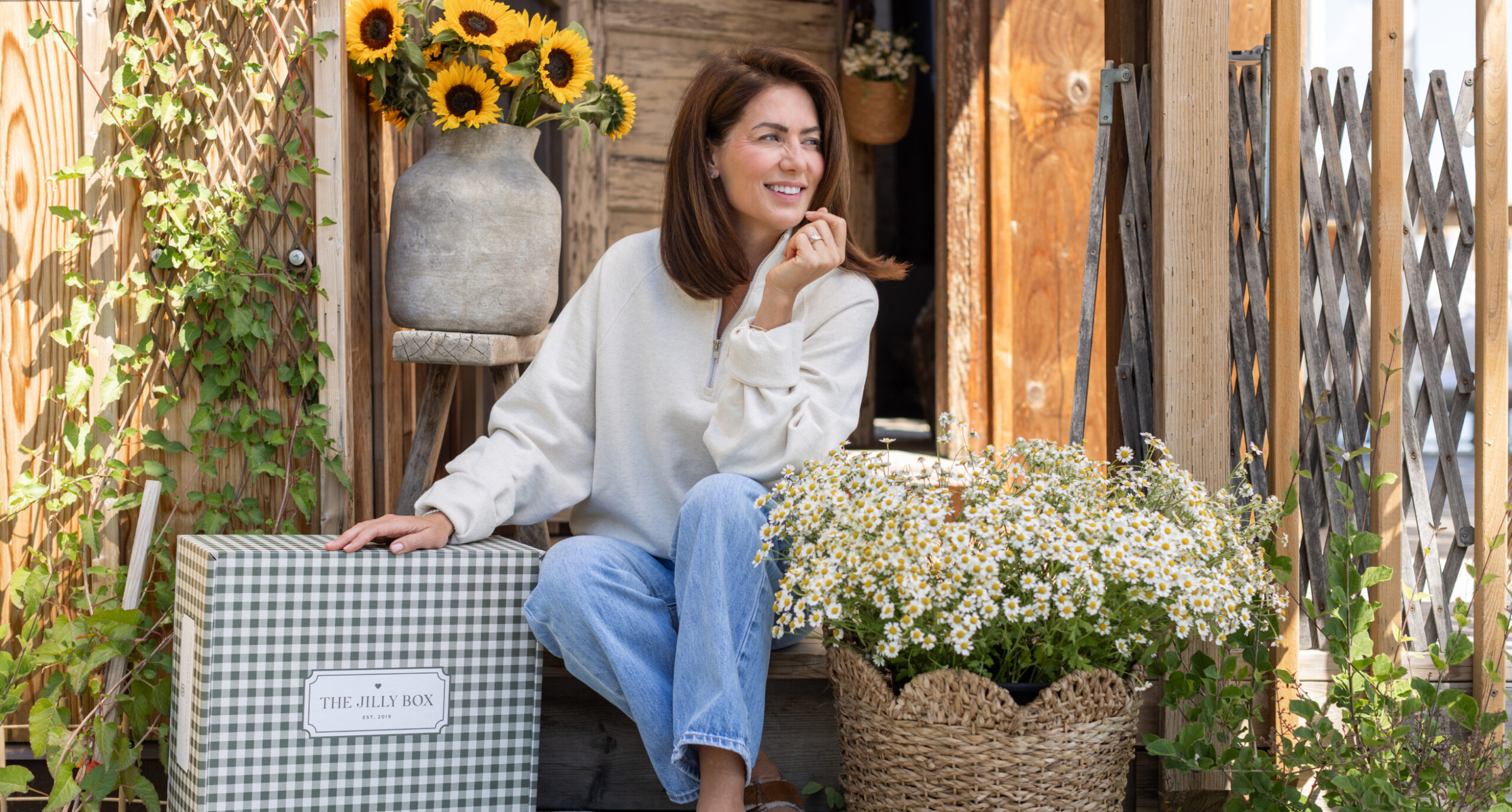 Jillian sitting on a porch with The Fall 2026 Jilly Box and flowers all around.